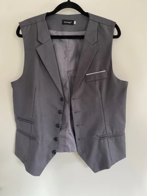 Grå Väst - Grå väst i märke DIKAGE. Storleken står XL men e ganska smal i passform så passar egentligen bättre till M-L