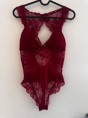 Spetsbody - Röd spetsbody med tjockare band, vaddering, utan bygel. Aldrig använd då den var lite för stor, dock är inga lappar kvar.