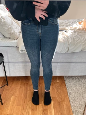 Blå skinny jeans  - Säljer ett par klassiska blå skinny jeans smal passform. Jeansen har fem fickor, dragkedja och knapp framtill samt snygga sömmar. Materialet är inte så stretchigt denim som sitter tajt och bekvämt.
