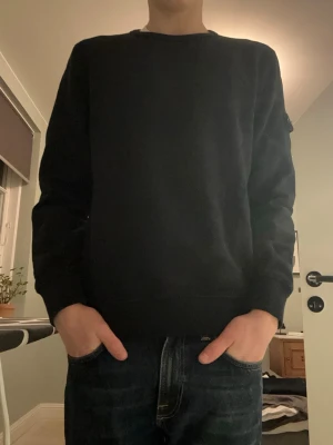 Stone Island sweatshirt - En svart sweatshirt från Stone Island. Det är junior storlek:14/170 men passar mig som är 184cm. Tröjan är köpt på NK i Göteborg. Använd endast ett fåtal gånger