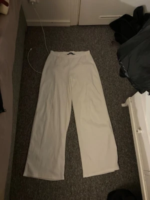 Vida vita mjukisbyxor - Säljer ett par vida mjukisbyxor i storlek S och de är low waist passform på byxorna. Materialet på byxorna är de som visas i andra bilden