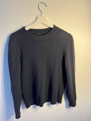 Mörkblå stickad Kashmir tröja Massimo Dutti - Mörkblå stickad tröja från Massimo Dutti i en mjuk ull- och kashmirblandning. Tröjan har rund halsringning, ribbade muddar och en klassisk, rak passform. Perfekt för dig som gillar stilrena och tidlösa plagg.