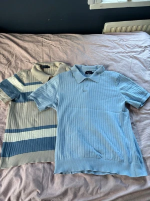 Ljusblå och Randig Piké av Riley - 2 pikéer, en ljusblå och en beige randig med vitt och blått. Dem är storlek L men sitter lite tajt på mig som är 82kg 180cm. Bra skick och defentivt värt pengarna om du vill ha piké till sommarn för bra pris. Jag kan använda dessa men skulle rekomendera till någon lite mindre än mig själv. Båda är samma storlek kan ej köpas separat