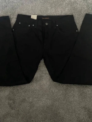 Helt nya svarta jeans från Nudie Jeans - Säljer ett par hel svarta jeans från Nudie Jeans med raka ben. Jeansen är helt nya med prislappen kvar. Ett par jeans som går bra till allt oavsett tillställning. Hör av er vid funderingar.