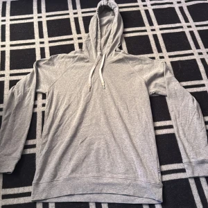 Grå hoodie från Mads Nørgaard - Snygg grå hoodie från Mads Nørgaard med vit snörning i huvan. Tröjan är i mjuk bomull och har en klassisk passform med långa ärmar. Perfekt för chill dagar eller när du vill ha en clean och enkel look.