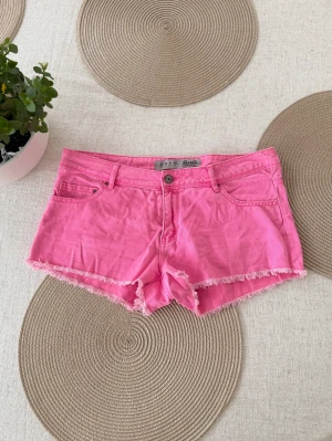 Rosa lågmidjade jeansshorts  - Storlek 40 (L). Rakt över midjemått: 41cm. Ingen bild på - för stora för mig. Skickas inom 24h. Se liknande plagg i min profil! 