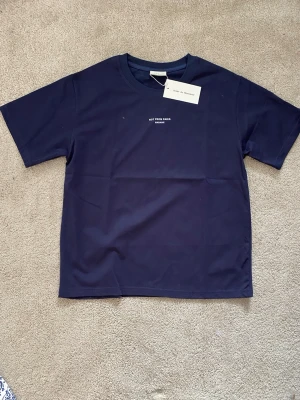 Blå t-shirt från Drôle de Monsieur - Mörkblå t-shirt från Drôle de Monsieur med trycket 'NOT FROM PARIS MADAME' på bröstet. Klassisk rund hals och korta ärmar. Tillverkad i mjuk bomull för en bekväm känsla.