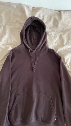 Brun hoodie från YOURTURN - Mörkbrun hoodie från YOURTURN med klassisk känguruficka och justerbar huva. Tillverkad i mjukt bomullsmaterial som känns skönt mot huden. Perfekt för en avslappnad och stilren look.