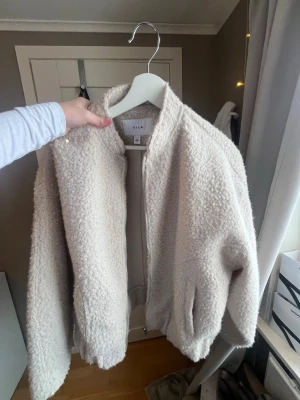 Creamfärgad bomberjacka från Vila - Mysig Creamfärgad bomberjacka från Vila med dragkedja framtill och ribbade muddar. 