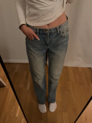 Blå raka jeans med medelhög midja - Säljer ett par klassiska blå jeans med rak passform och medelhög midja. Jeansen har fickor, bälteshällor och knappgylf. Materialet är denim  och färgen är ljusblå tvätt. Perfekta till en avslappnad stil.