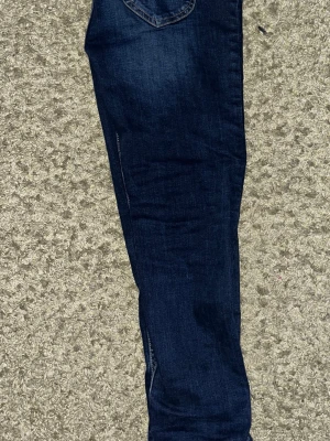 Lee jeans  - Säljer ett par mörkblå s jeans med klassiska bakfickor och kontrastsömmar. Jeansen har en smal passform och är tillverkade i stretchigt denimtyg för extra komfort. Perfekta för en avslappnad och trendig look.