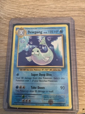 Pokémonkort Dewgong 29/108 - Säljer ett Pokémonkort med Dewgong, nummer 29/108 från 2016. Kortet har blå och gula kanter, och Dewgong syns simmande under vatten med bubblor runt sig. Kortet är inplastat i ett skyddsfodral.