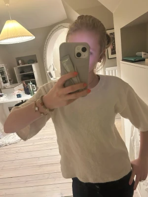 Vit stickad topp med korta ärmar - Säljer en vit stickad topp med korta ärmar och rund halsringning. Toppen har en enkel och clean design, perfekt att matcha med jeans eller kjol. Materialet ser ut att vara mjukt och bekvämt, och modellen är lite boxig. Skriv vid frågor 💕💕