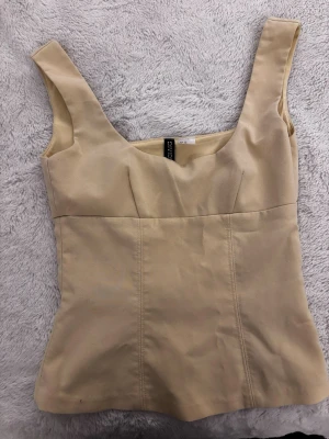 Gul linnetopp från hm - Snygg beige linnetopp från Divided med breda axelband och figurnära passform. Den är ganska tight över. Är XS men kanske passar bättre för XXS