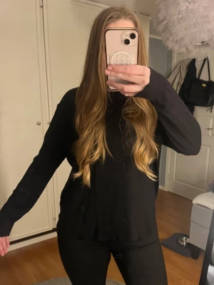 Svart stickad tröja i basic stil - En enkel svart stickad tröja med rund hals och långa ärmar. Tröjan har en rak passform och är perfekt för lager på lager. Materialet ser mjukt och bekvämt ut, perfekt för kyligare dagar.