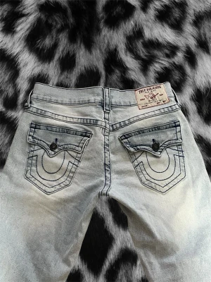 Lowwaist true religion bootcut jeans  - Säljer dessa supersnygga true religion jeansen i modellen billy som är använda 1 gång. De har mörkblå sömmar! Köpta för ca 2000kr i Stockholm! Storlek 28, passar en S/M beroende på hur man vill att de ska sitta. Unisex så passar både tjejer o killar. Midjemått rakt över: 40cm innerbens längden: 81cm,  från hela midjan upp ifrån och ner till slutet av benet: 105cm. Brukar ha 36 i jeans för referens. Super liten skarpa längst ner som är omärkbar! 
