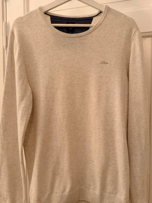 *DUNDER* Beige stickad tröja från s.Oliver - Säljer en stilren beige stickad tröja från s.Oliver. Tröjan har rund halsringning, långa ärmar och diskret logga broderad på bröstet. Perfekt basplagg till garderoben och enkel att matcha med olika outfits.