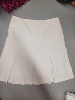 Vit kortkjol med veck - Säljer en stilren vit kjol, jätte fin bara använd ett fåtal gånger. Dragkedja bak. 