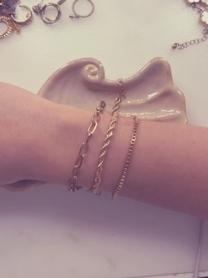 Tre guldiga kedjearmband - Säljer tre stilrena armband i guldfärgad metall. Ett har större ovala länkar, ett är tvinnat och ett har platta, tunna länkar. Perfekta att bära tillsammans eller var för sig för en trendig look. Passar dig som gillar minimalistiska och klassiska accessoarer. En för 10 alla för 25.  Gå in på mitt konto jag säljer FLERA smycken i olika former och färger. 