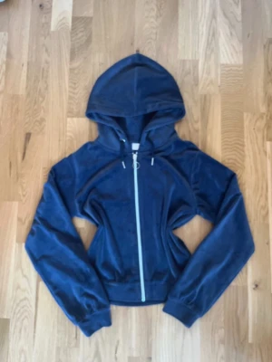 Mörkblå velour hoodie med dragkedja - Snygg mörkblå hoodie i mjuk velour med dragkedja framtill och huva med dragsko. Tröjan har långa ärmar och ribbade muddar. Perfekt för en chill och avslappnad stil.