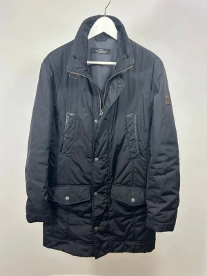 Corneliani Jacka Svart - Stilren svart parkas från Corneliani i fin kvalitet. M men slim fit. Modellen är 175 cm och väger 70 kg. Inga defekter eller anmärkningar, fint skick! Jackan är en tunnare vinterjacka i modellen ”Berlin Light”.