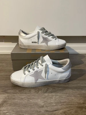 Golden Goose skor - Tjena säljer ett par sköna Golden Goose skor i färg vit och grå. Väldigt classy o snygga. Helt nya box och påse medföljer såklart🫡💝