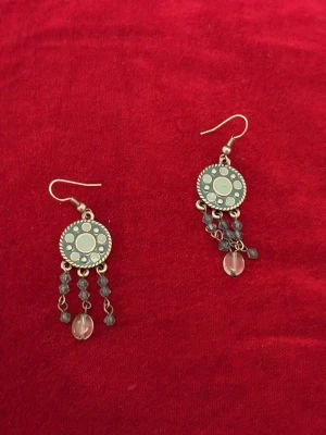 Boho örhängen med pärldetaljer - Unika örhängen med rund turkosfärgad platta dekorerad med prickmönster. Tre hängande kedjor med små blå pärlor och en större genomskinlig pärla längst ner på varje örhänge. Metallkrokar i silverfärg. Perfekt för dig som gillar boho-stil och detaljer.