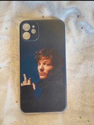 Mobilskal med mörk design och motiv - Snyggt mobilskal med mörk bakgrund och motiv av Louis Tomlinson som visar fingret. Skalet har en matt finish och är gjort av plast. Passar till iPhone 11. Perfekt för dig som vill ha ett edgy och unikt skal.