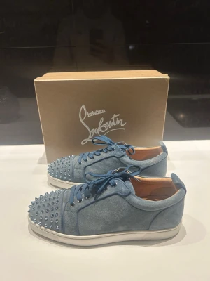Blåa Christian Louboutin sneakers - Säljer ett par blåa sneakers från Christian Louboutin i mocka med matchande blå skosnören och coola nitar på tån. Skorna har vit sula och en snygg låg profil. Perfekta för våren och sommaren. De e i mycket bra skick här nästan aldrig använt dem så dem ser nya ut. Storlek 44,pris kan diskuteras, allt tillbehör ingår. Mer frågor skriv bara 👍