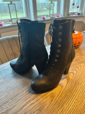 Svarta snörade stövletter Gardinia - Säljer ett par svarta stövletter från Gardinia med snörning framtill och dragkedja på sidan. Skorna har chunky klack och är tillverkade i ett strukturerat syntetmaterial som liknar läder. Snygg retrovibe och passar perfekt till höstens outfits.