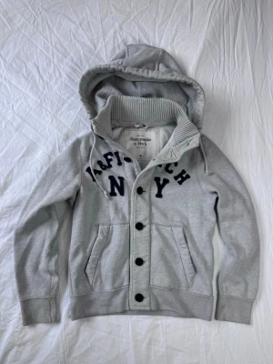 Grå kofta från Abercrombie & Fitch - Säljer nu en Abercrombie and Fitch Kofta👕                                                              Storlek: M, Skick: 9/10, Skriv vid minsta fråga, Fraktar alltid inom 24h efter köp📦