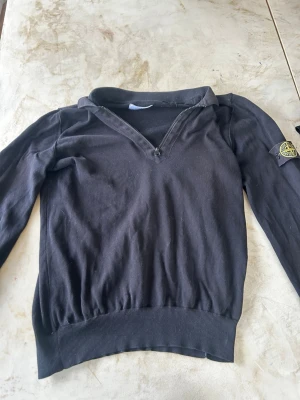 Svart Stone Island tröja med dragkedja - Svart långärmad caseytröja från Stone Island med klassisk patch på är`:men. Tröjan har en kort drag sop vid hals uns och ribbade muddar vid midja och ärmslut. out ett stilrent och sportigt plaggad för dig som gillar streetwear. Priset går att diskutera 