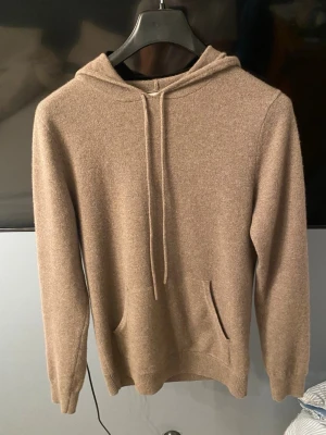 John Henric Kashmir hoodie S - Mjuk och lyxig beige hoodie från john Henric i cashmere. Klassisk modell med huva och magficka framtill. Tröjan är i strl S. Tröjan är i bra skick förutom ett jätte litet hål som visas på bild 4,5 och de märks inte av och syns inte vid användning.