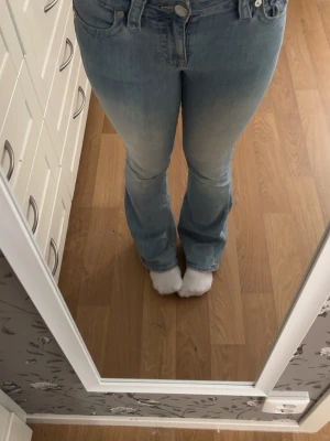 Ljusblå bootcut jeans från Rock & Republic - Säljer ett par ljusblå bootcut jeans från Rock & Republic med snygga slitningar och markerade sömmar. Jeansen har en cool fickdesign bak med knapp och logotyp på läderpatch. Perfekt passform och klassisk denimlook.