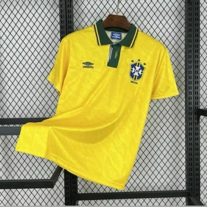 Gul Brasilien fotbollströja Umbro - Klassisk gul fotbollströja från Umbro med Brasilien-emblem på bröstet. Tröjan har gröna detaljer på kragen och knäppning, samt korta ärmar. Perfekt för dig som älskar fotboll och vill representera Brasilien med stil.