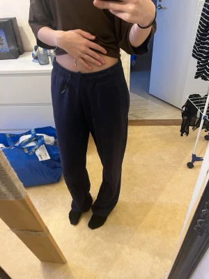 Mörkblå mjukisbyxor med dragsko - Säljer ett par mörkblå mjukisbyxor med avslappnad passform och resår i midjan samt dragsko för justerbarhet. Byxorna är raka i modellen3. Heter: Elevated basics