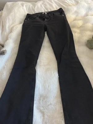Svarta bootcut jeans - Säljer ett par svarta bootcut jeans med klassisk femficksdesign och normal midja. Jeansen har en lätt utsvängd passform nedtill och är tillverkade i ett mjukt denimtyg. Perfekta för dig som gillar en tidlös och avslappnad stil.