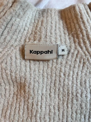 Beige stickad tröja från Kappahl - Mysig beige stickad tröja från Kappahl i storlek M. Tröjan har en ribbad struktur och rund halsringning. Perfekt för lager på lager och enkel att matcha med olika outfits.