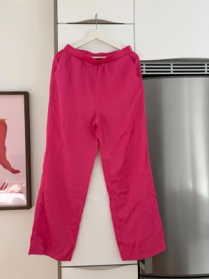 Rosa mjukisbyxor från Vero Moda - Säljer ett par snygga rosa mjukisbyxor från Vero Moda. Byxorna har en avslappnad passform med resår i midjan och raka ben. Perfekta för chill dagar hemma eller när du vill ha en färgklick i garderoben. Tillverkade i mjukt och skönt material.