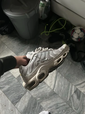 Nike Air Max Plus vita sneakers - Nike Air Max Plus sneakers i vitt med mesh- och syntetpaneler, ikoniska vågiga linjer och synliga Air-enheter i sulan. Snygg och sportig design med svarta och grå detaljer. Perfekta för dig som gillar streetwear och klassiska sneakers. Lite smutsiga men man kan tvätta så blir dem mycket renare!! Äkta köpte på Nike hemsida för 2200kr