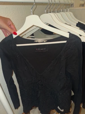 Svart spetsblus från OddMolly - Svart långärmad blus från Odd Molly, broderade detaljer och spets nertill. Storlek 0