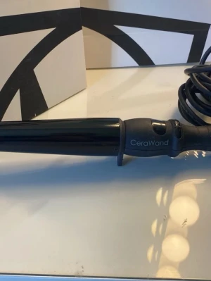 Svart locktång CeraWand - Säljer en svart locktång från CeraWand med sladd och ergonomiskt handtag. Tången har en konformad form och är tillverkad i plast och metall, perfekt för att fixa snygga lockar snabbt och enkelt.