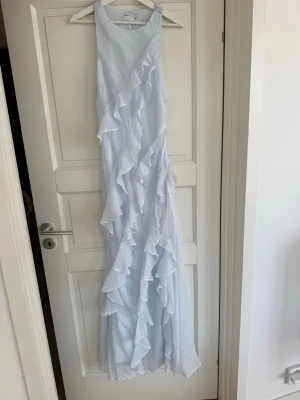 Ljusblå maxiklänning med volang  - Ljusblå superfin maxiklänning med volangdetaljer. Klänningen är luftig och skön då den inte sitter åt och faller superfint. Perfekt till bal eller bröllop.