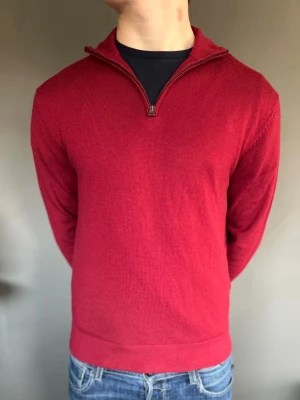 Röd halvzip tröja - Snygg röd tröja med halv dragkedja och ståkrage. Tillverkad i mjuk ullmix som känns skön mot huden. Långärmad modell med ribbade muddar och enkel, stilren design som passar till jeans.