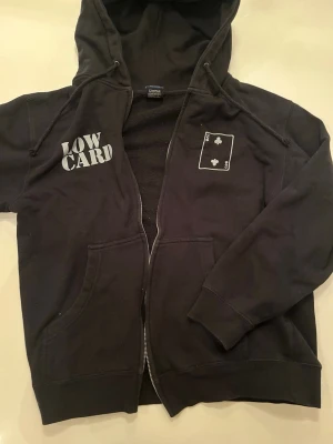 Low Card - Svart hoodie med dragkedja från Low Card. 