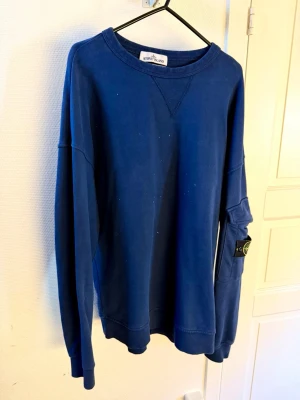 Sweater, Stone Island - Mörkblå sweatshirt från Stone Island med klassisk rund halsringning och ribbade muddar. Tröjan har dess ikoniska patch på vänster ärm och är tillverkad i mjuk bomull. Tillverkad i Italien. Inköpt på Jupiter föe 2999:-