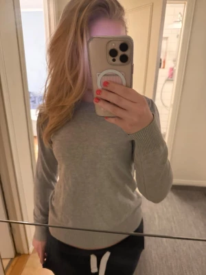 Grå stickad tröja från Saint tropez. - Säljer en enkel och stilren grå finstickad tröja från Saint. Tröjan har rund halsringning, långa ärmar och ribbade muddar vid ärmslut och nederkant. Perfekt basplagg till garderoben och lätt att matcha med olika stilar.