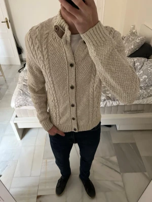 Beige stickad kofta med knappar - Säljer en beige stickad kofta med kabelstickade detaljer i storleken M.                                                   ———————————————————————————                                                      📐| Storlek: M                                                          👖| Märke: Massimo Dutti                                      🔎| Skick: Fint skick                                               ✍🏻| Skriv om du har några frågor