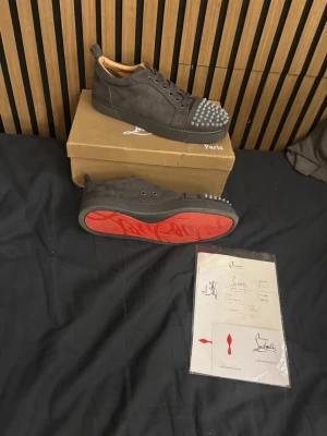 Gråa Loubs med nitar - Säljer dessa louboutins då jag ej använder de. Skorna är gråa med nitar och den klassiska röda sulan, Skorna är använda ett fåtal gånger. Säljer dessa jätte billigt. Man får med kvitto och resterande i plats fickan som man ser på bilden.