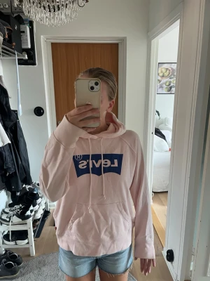 Ljusrosa hoodie - Ljusrosa hoodie med marinblått tryck på ifrån Levi’s. Nypris 699kr.  Storlek S och normal i storlek.